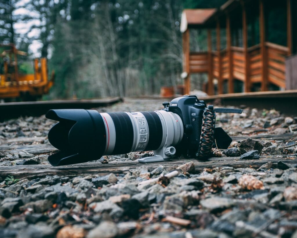 white and black DSLR camera on stone-filled ground near wooden establishment